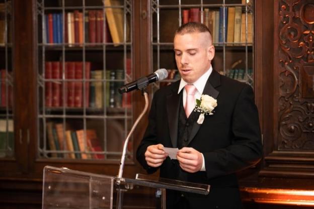 A man in a suit reads from a piece of paper in front of a podium